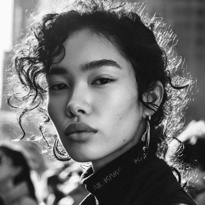 Black-and-white editorial beauty portrait of a woman with softly curled hair.