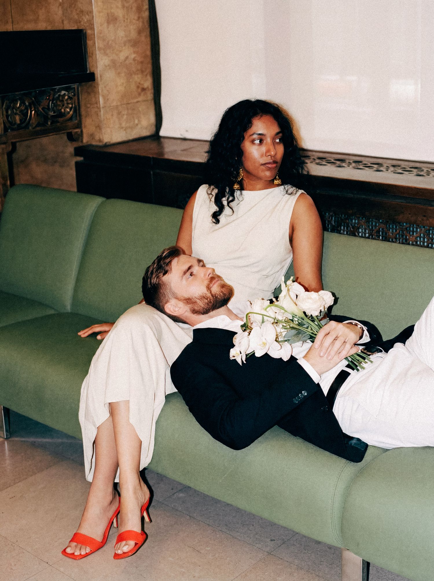 Playful newlywed couple relaxing together on a green lounge.