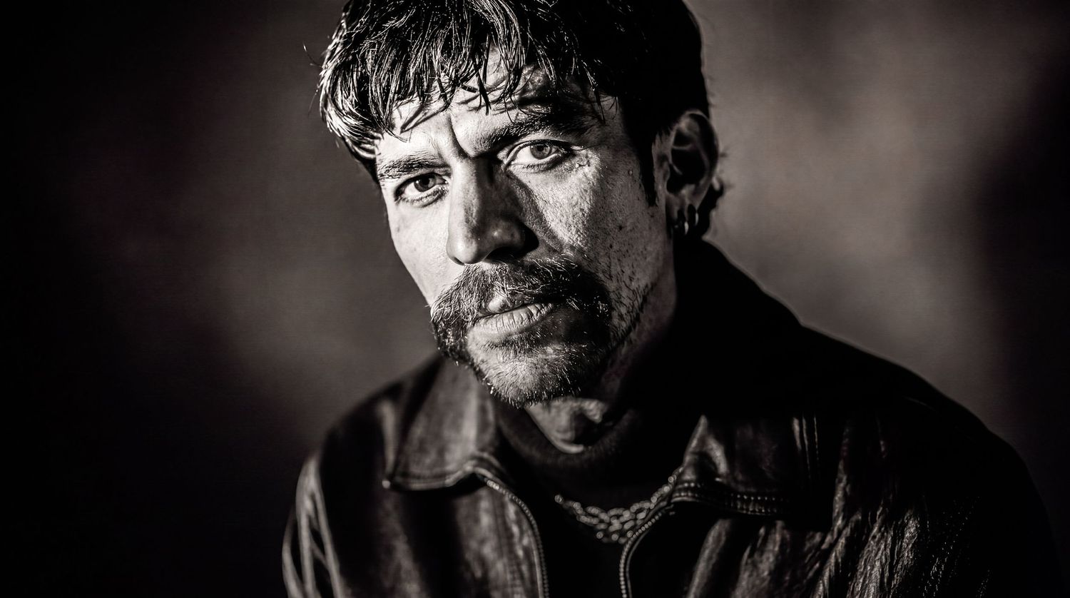 Dramatic black-and-white portrait of a man with a mustache and textured jacket.