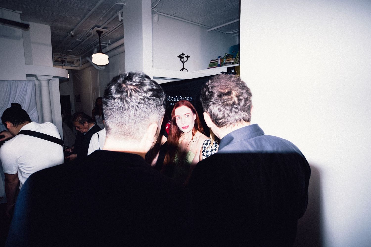 Guest being photographed during a crowded Soho fashion gathering.