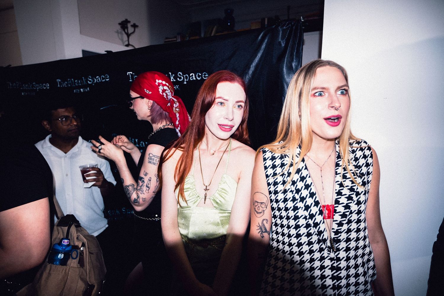 Two stylish guests reacting together at a Soho fashion event.