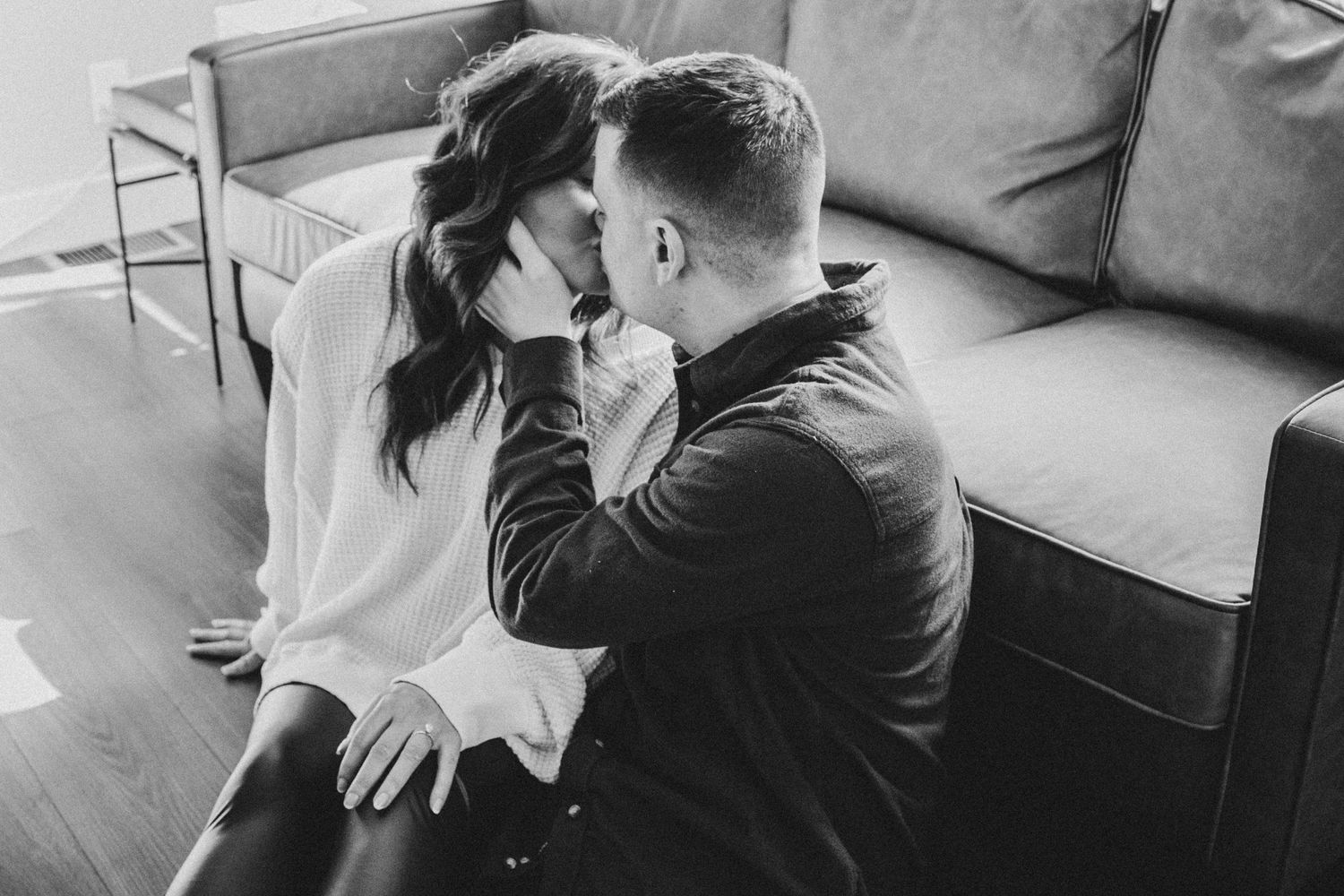 Intimate black and white photo of couple sharing a tender moment on a couch.