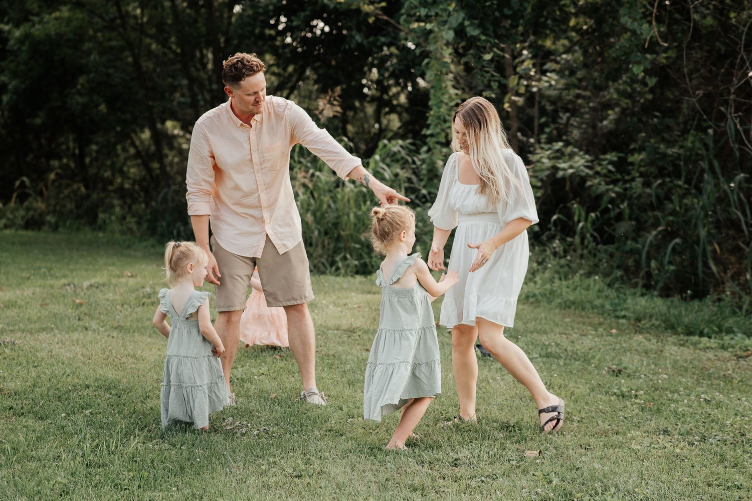A joyful family moment captured while playing together in a sunlit green field.