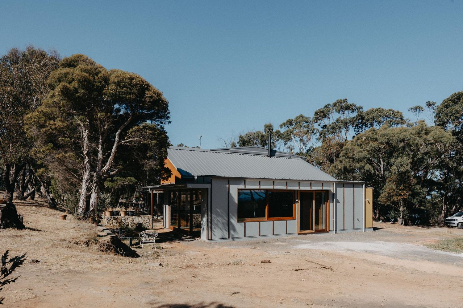 Contemporary rural home with dark metal roof, timber accents and large glazed windows set among native eucalyptus trees.