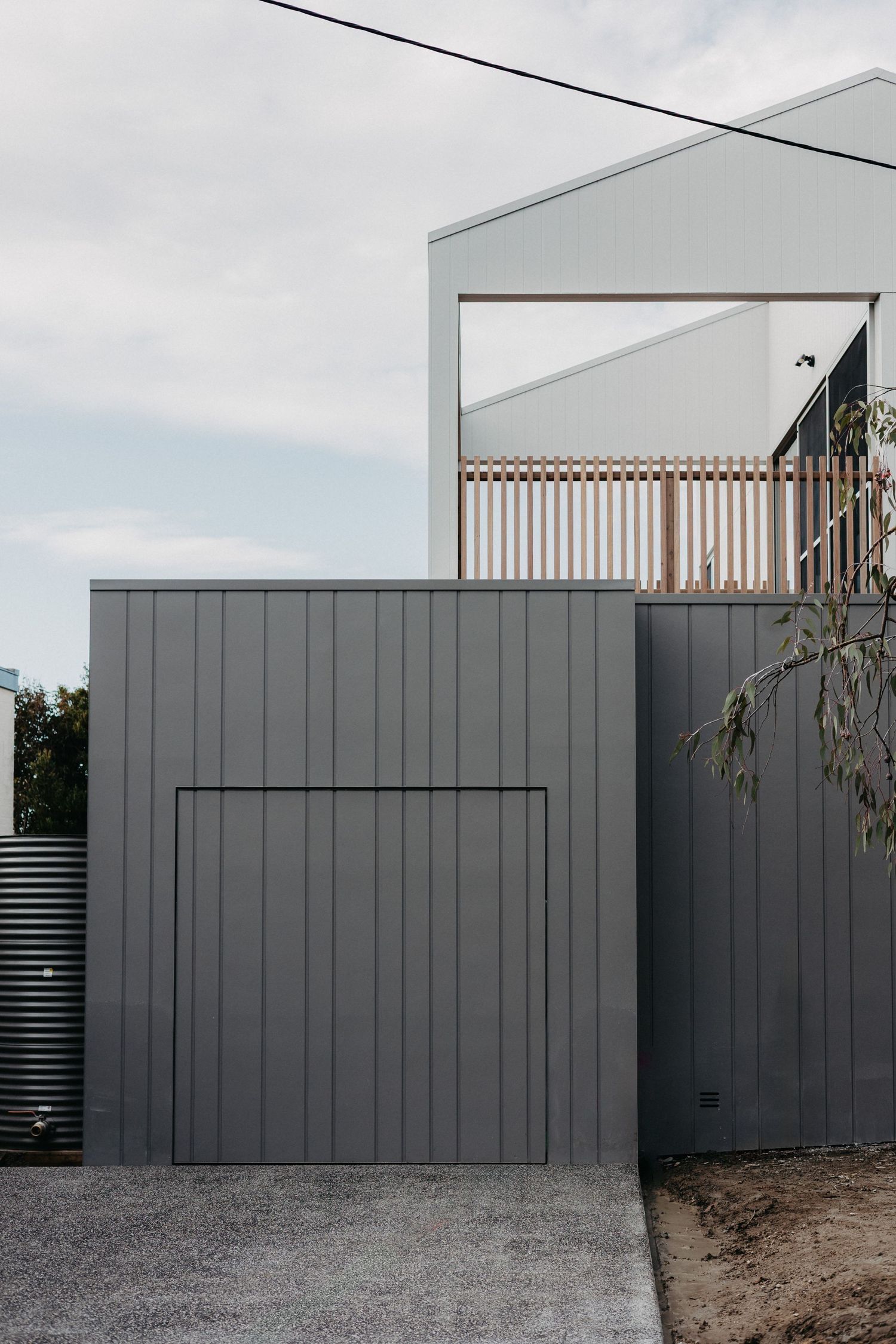 Modern grey vertical cladding facade with timber balustrade balcony and integrated garage door in contemporary Australian home design.