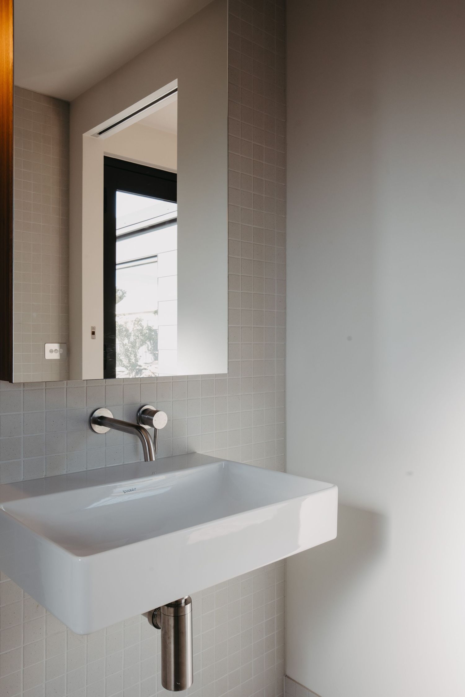 Minimalist bathroom featuring a white rectangular wall-mounted Duravit sink with chrome faucet and square mirror above.