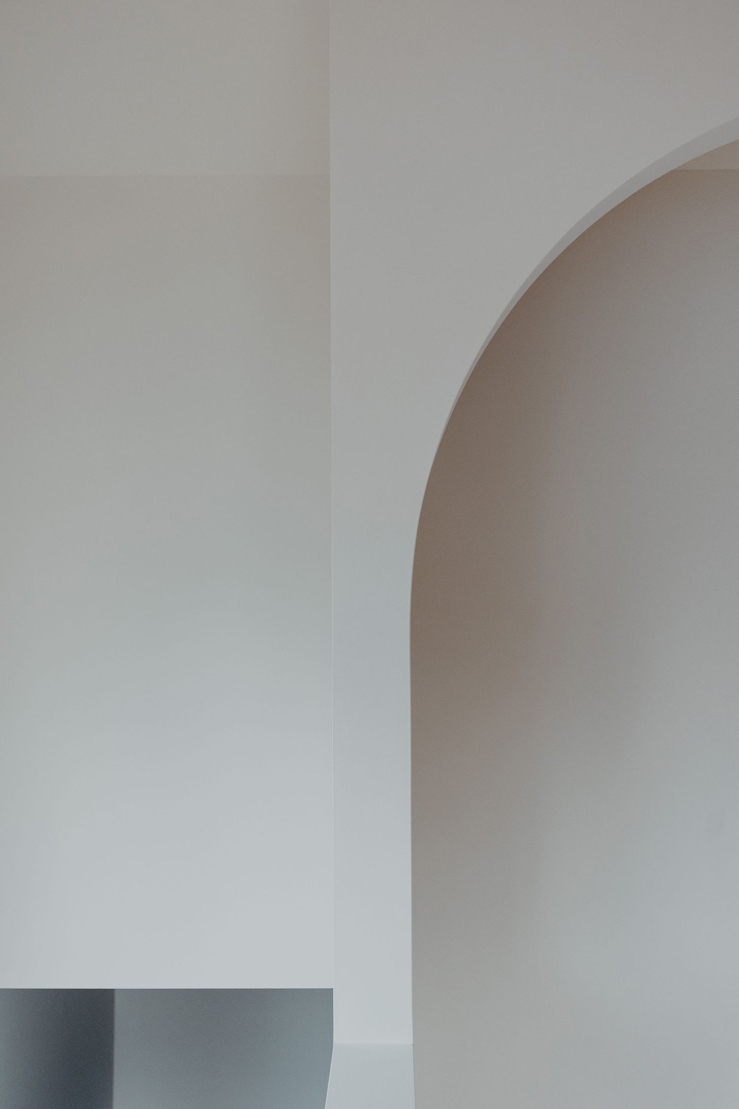 Minimalist interior featuring a smooth white arched doorway with clean lines and soft neutral tones.