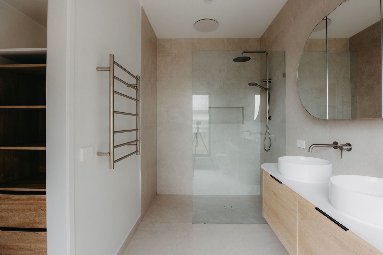 Modern bathroom with timber double vanity, vessel sinks, walk-in shower, and brushed nickel heated towel rail.