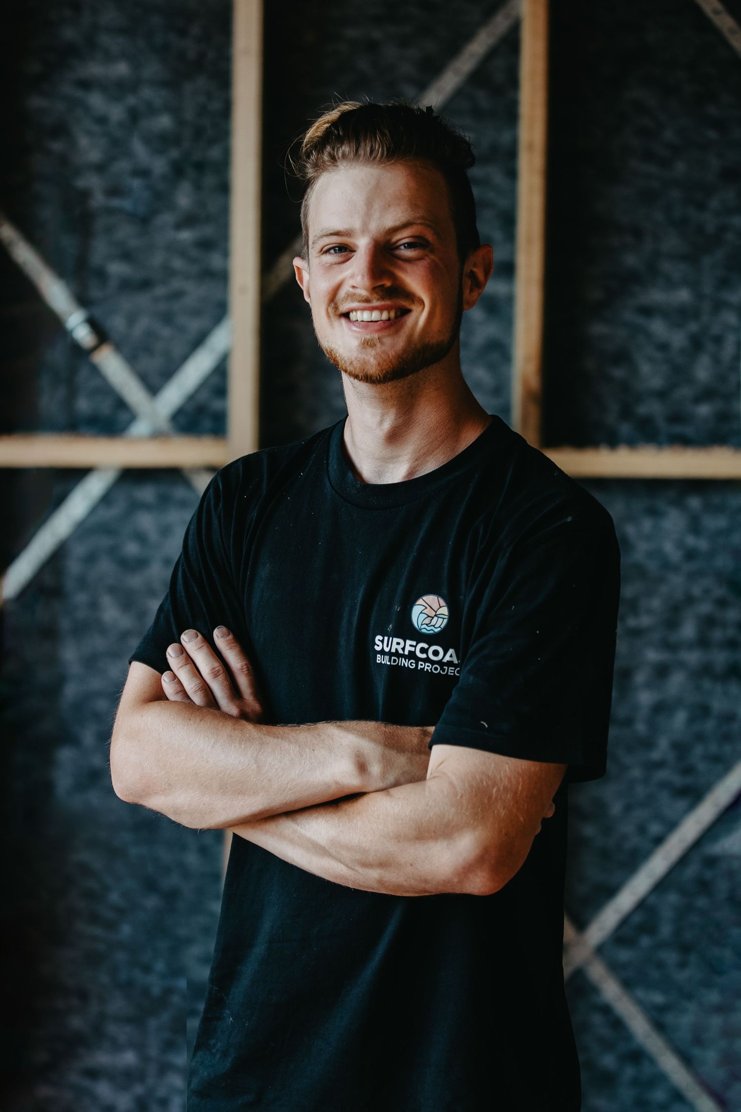 Smiling young man in black Surfcoast t-shirt with arms crossed.