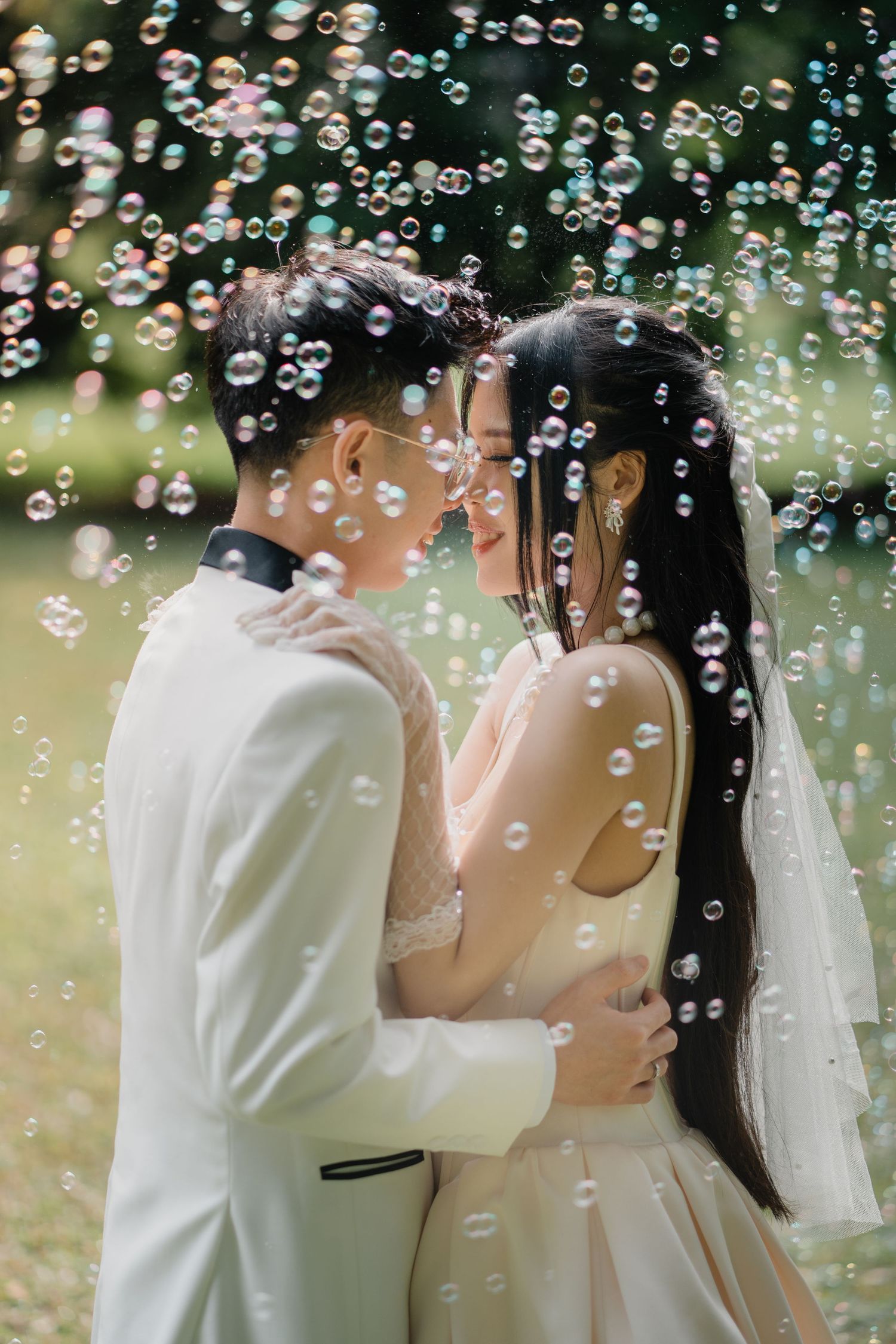 A bride and groom share a romantic moment surrounded by floating bubbles outdoors on their wedding day.