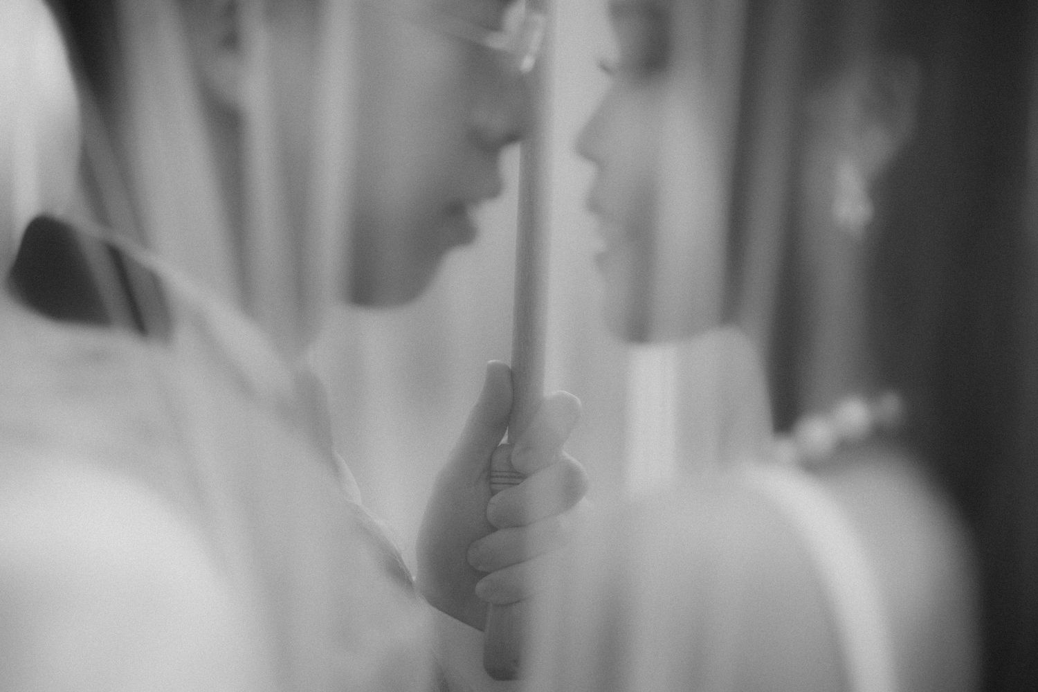 Black and white wedding photo of bride and groom sharing intimate moment under veil.