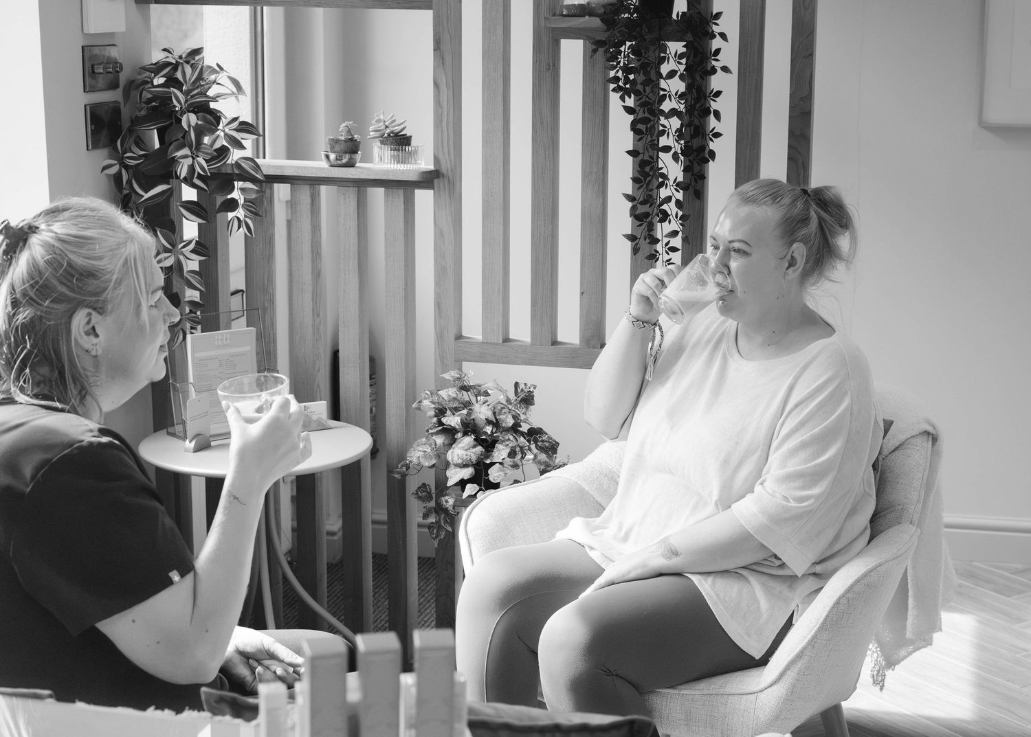 Black and white image of two women having a relaxed consultation in a beauty salon.