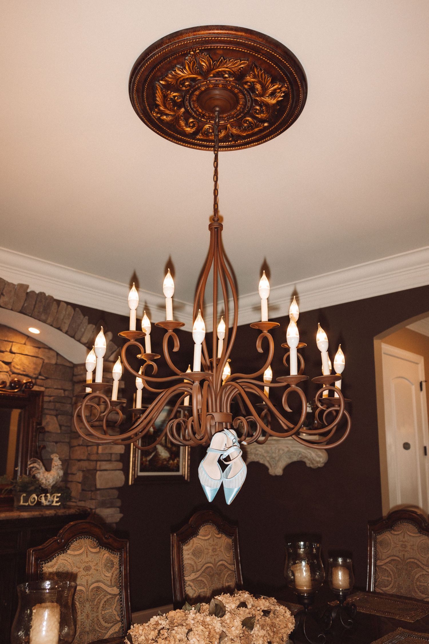 Ornate bronze chandelier with candle lights hanging from decorative ceiling medallion in elegant dining room.