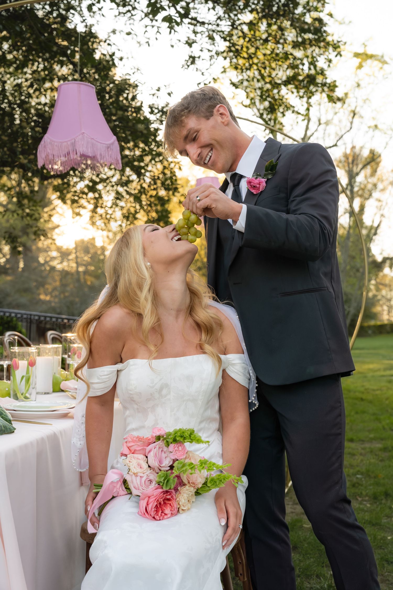 Smiling bride and groom share a joyful moment outdoors at a garden wedding reception at golden hour.