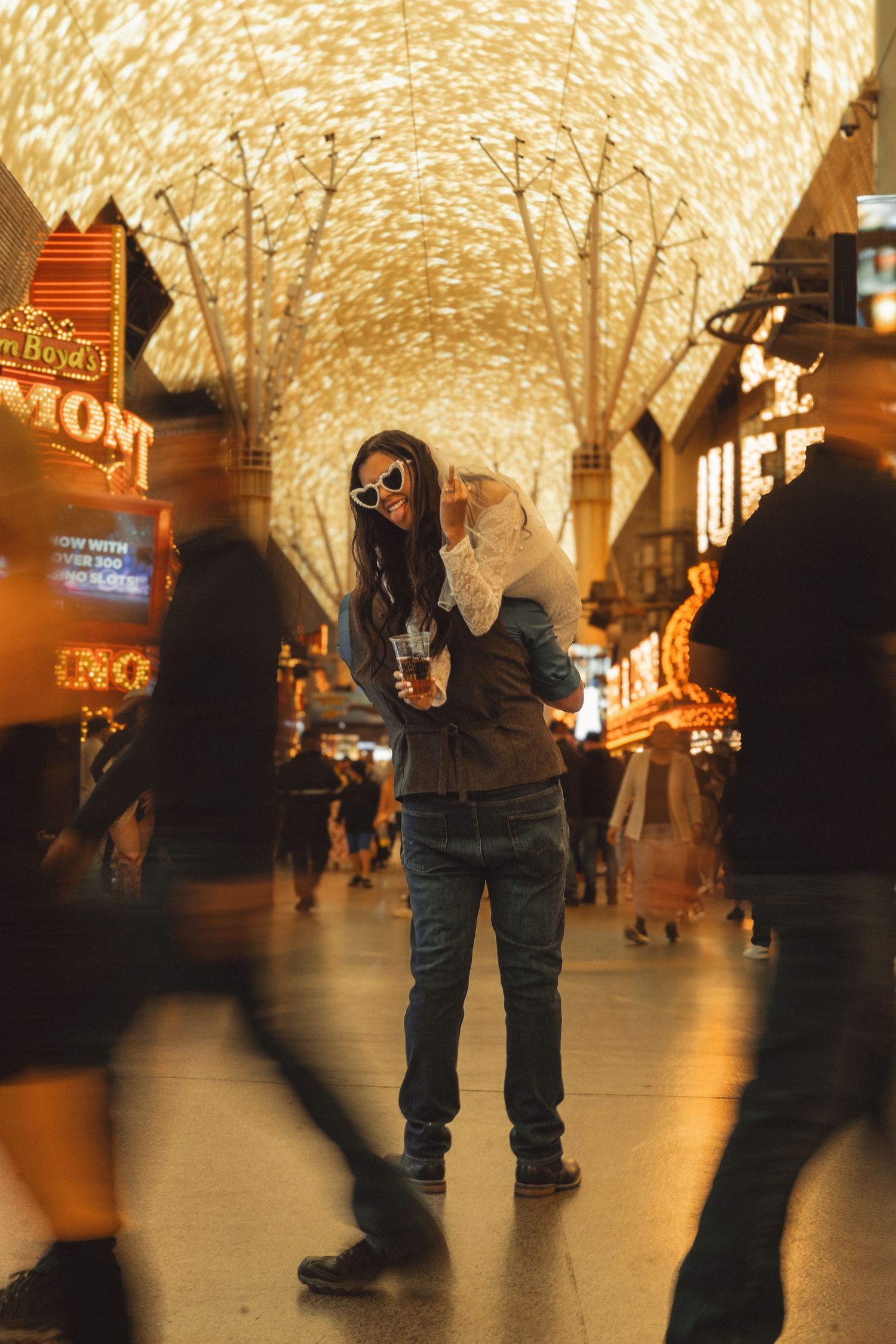 Person standing under glowing Fremont Street Experience canopy in Las Vegas, holding a child amid blurred crowd.