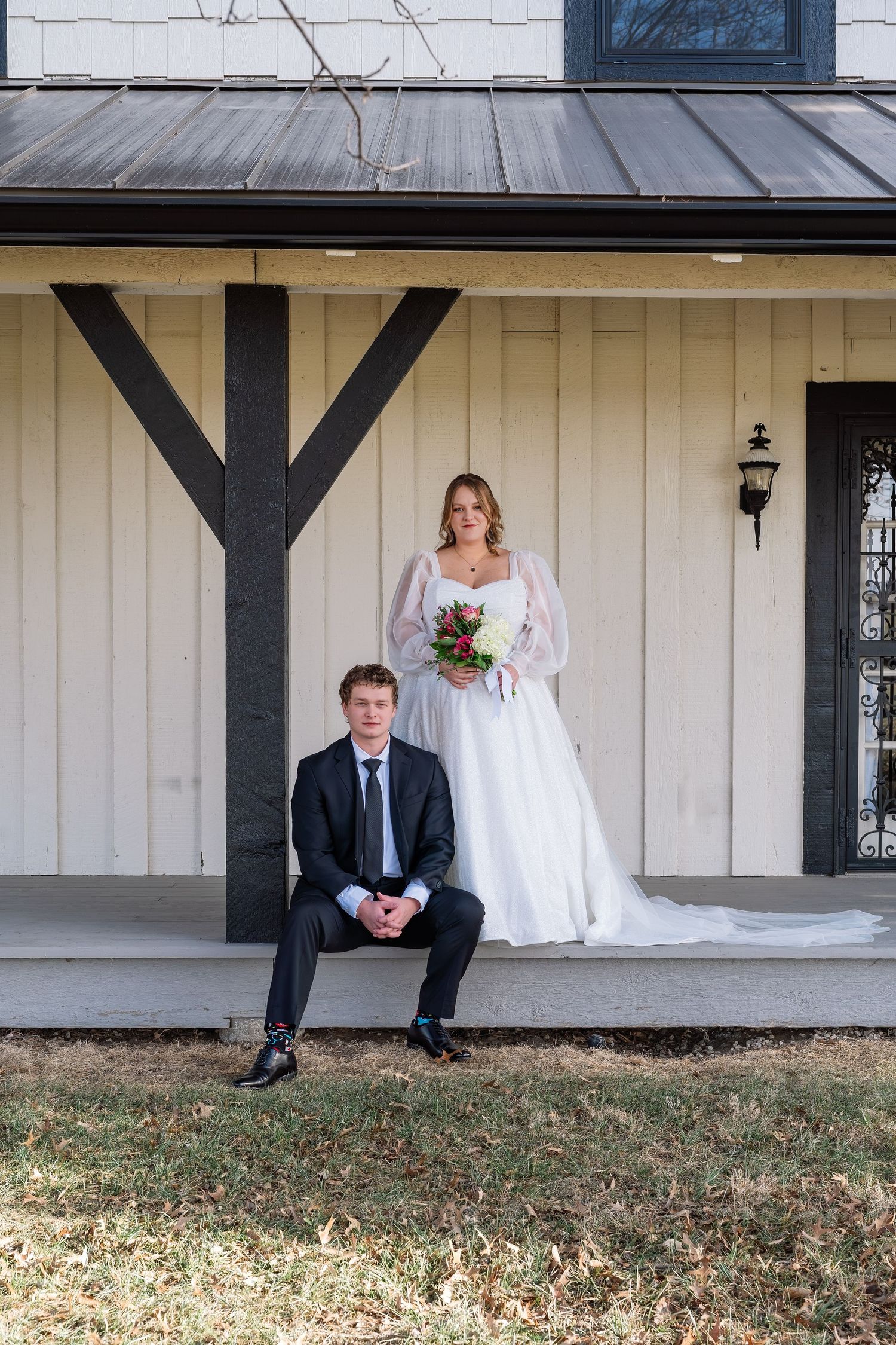 Bride and groom posing on a rustic farmhouse porch.