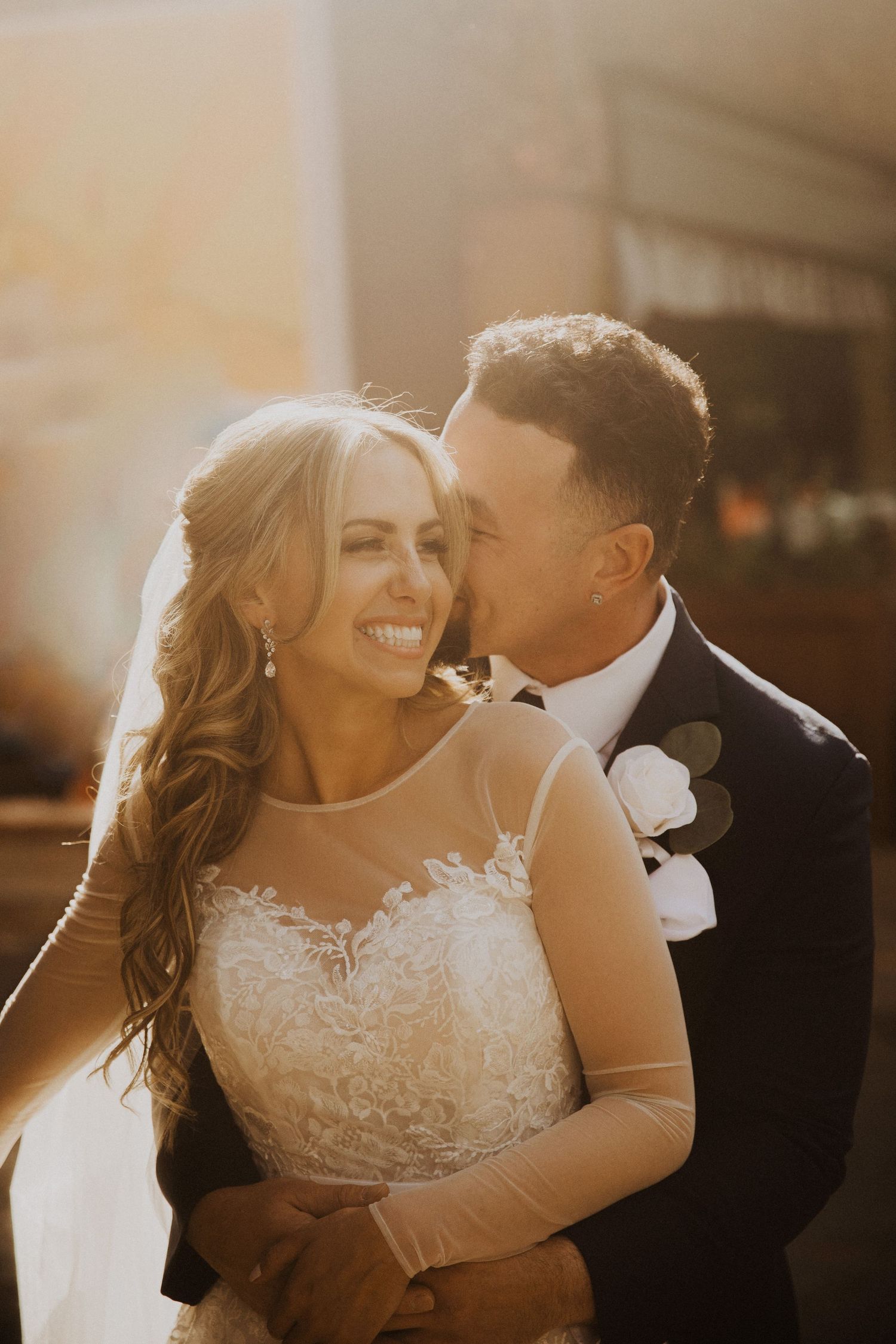 Romantic sunset portrait of newlyweds embracing in golden hour light.