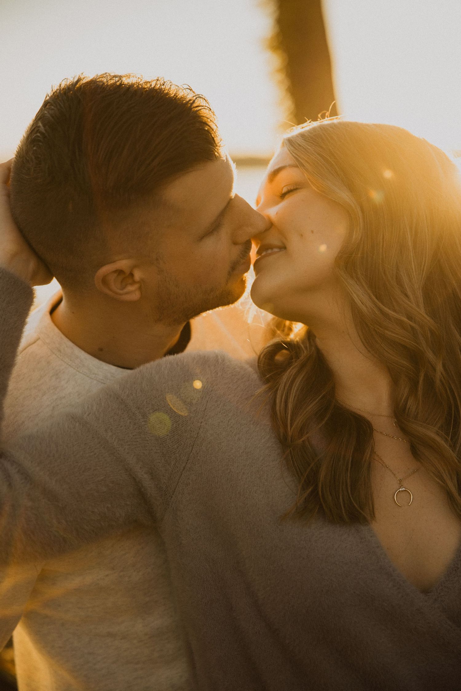 A couple sharing intimate kisses in warm golden sunlight.