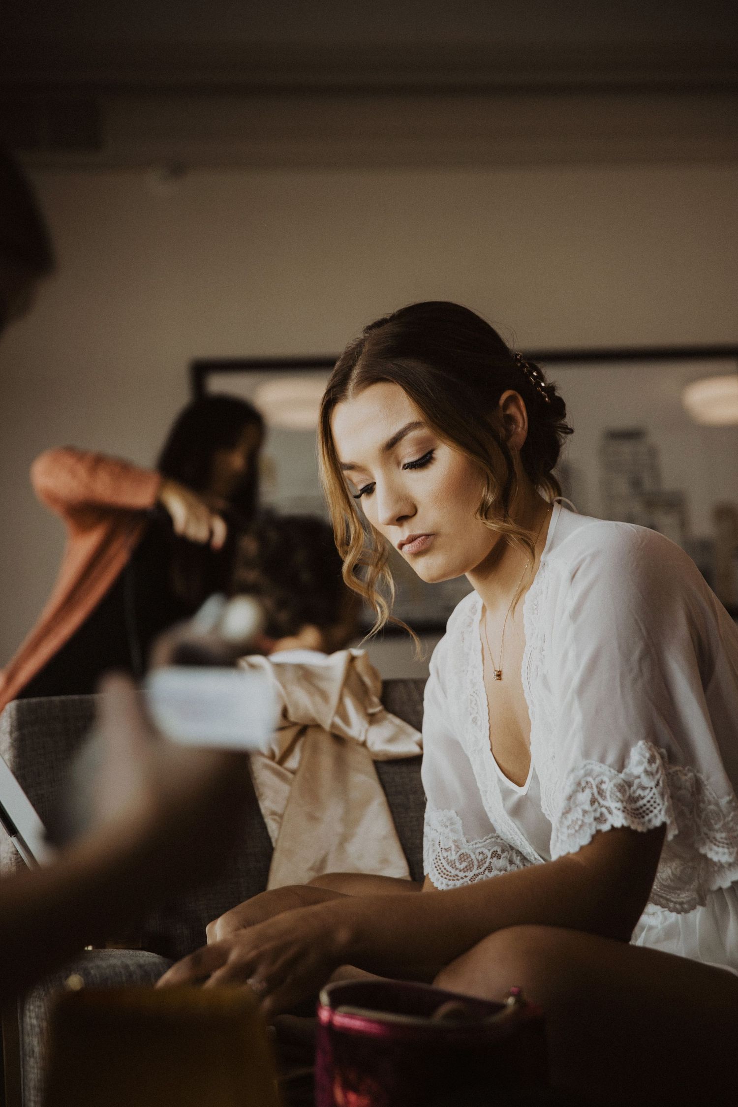 Bride in white lace robe getting ready before wedding ceremony.
