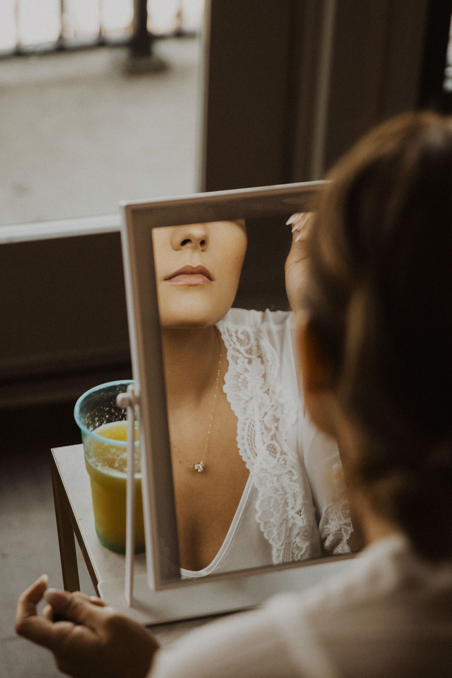 Close-up reflection of bridal details in mirror during wedding preparation.