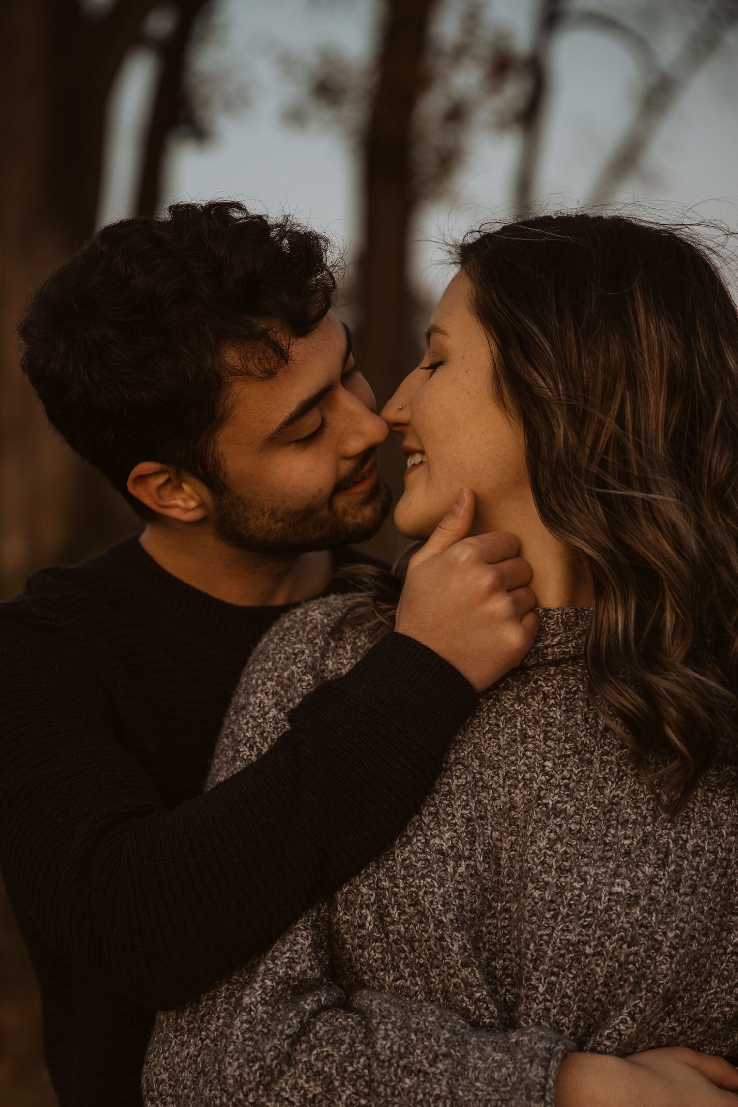 Intimate portrait of couple in warm lighting sharing tender moment outdoors.
