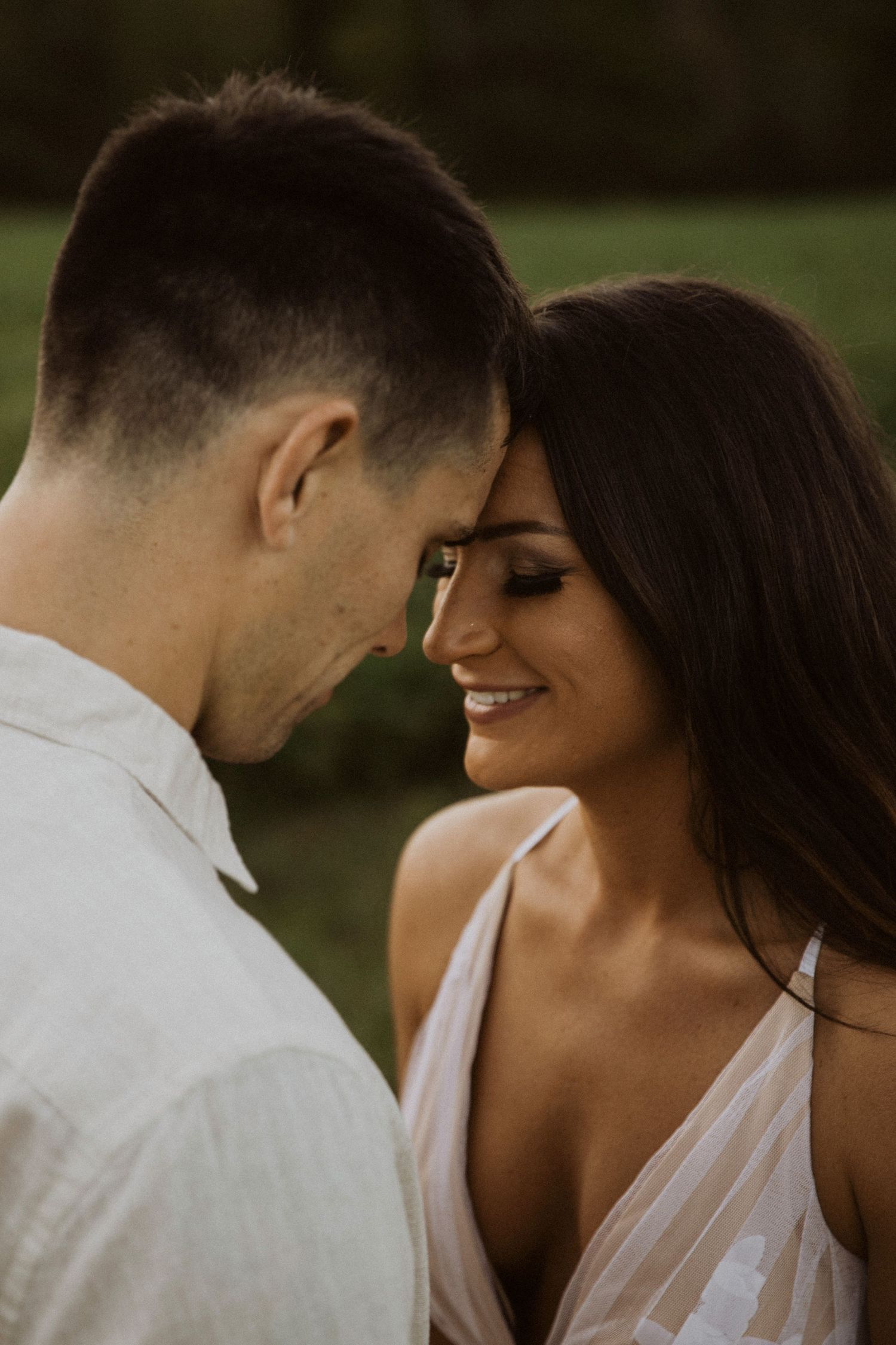 A couple shares an intimate moment while dressed in white and grey attire.