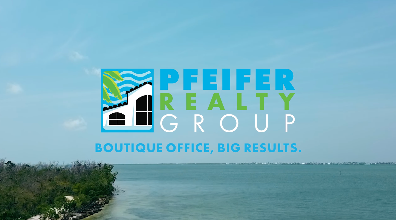A scenic beachfront view with palm trees and buildings along the coastline under a bright blue sky.