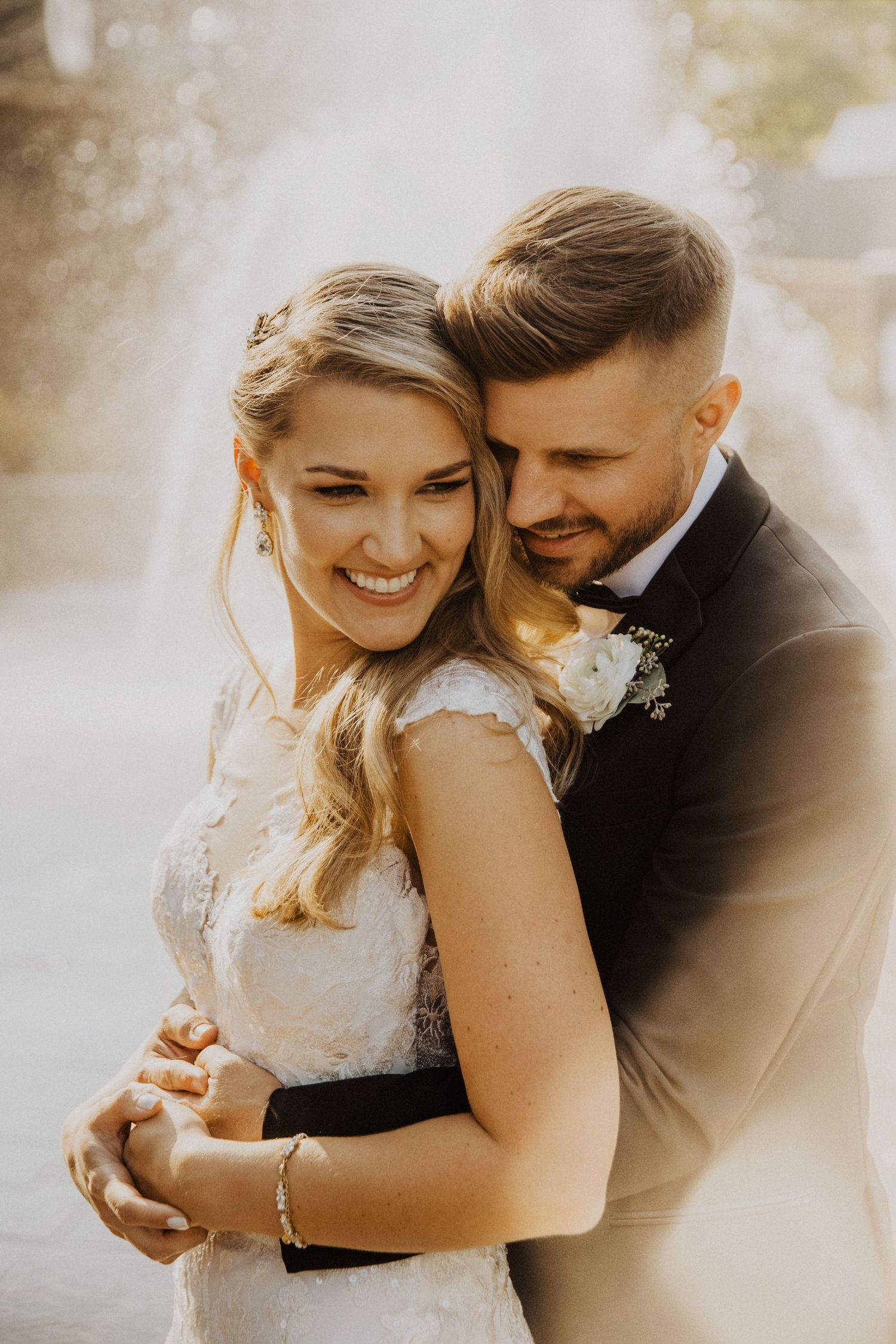 Sun-drenched portrait of newlyweds sharing intimate moment outdoors.