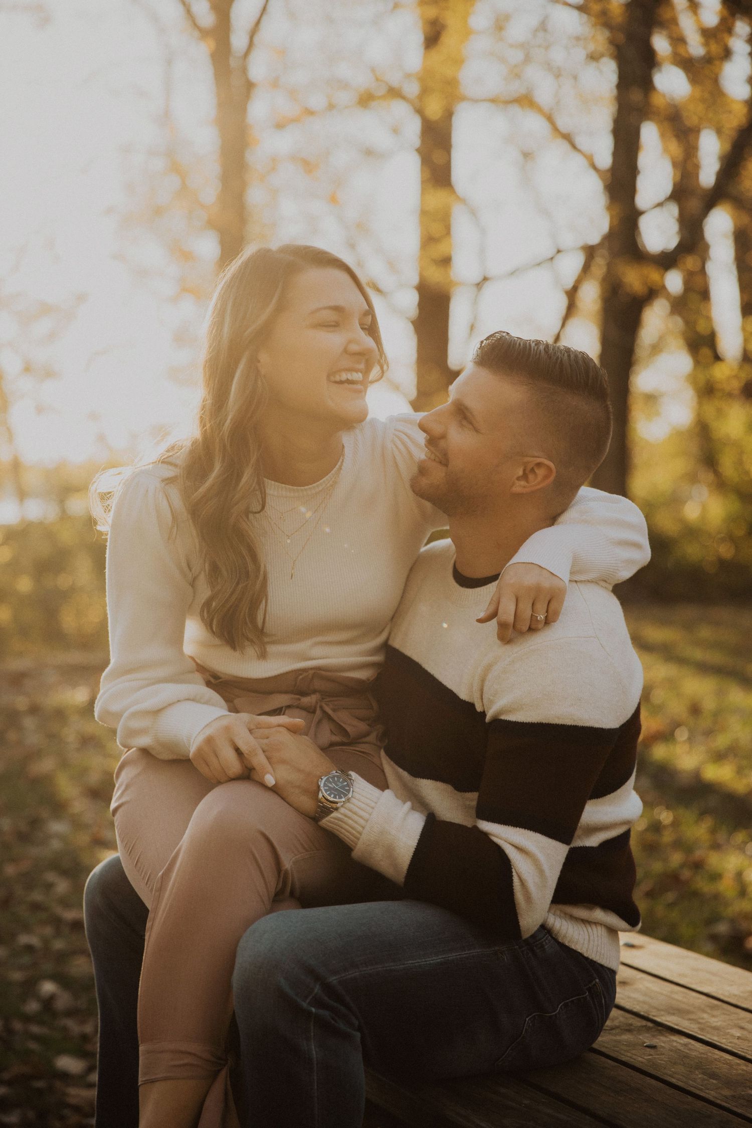 A couple sharing joyful moments while sitting together on a bench in autumn.