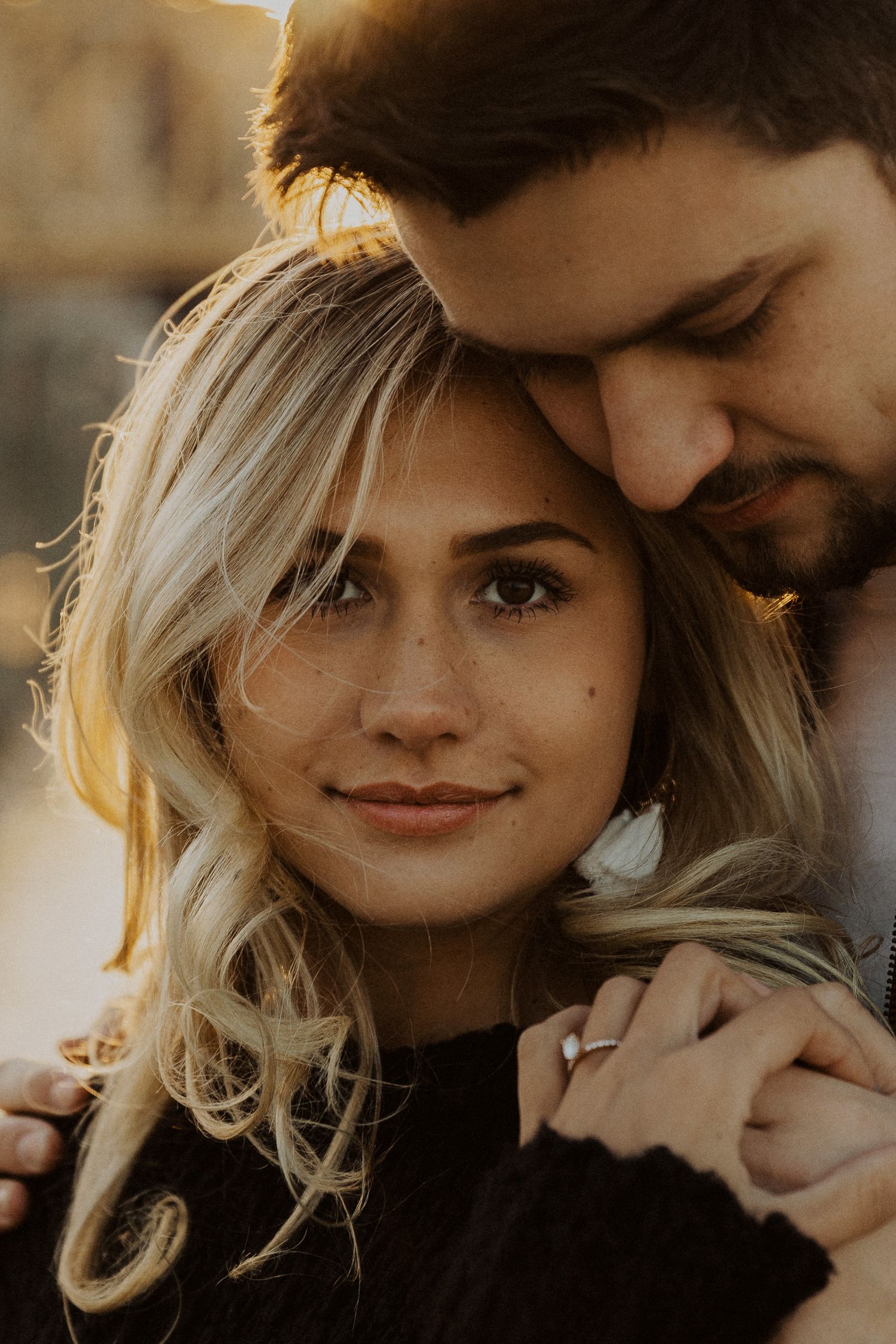 Romantic couple sharing intimate moments in warm golden sunlight during sunset photo session.