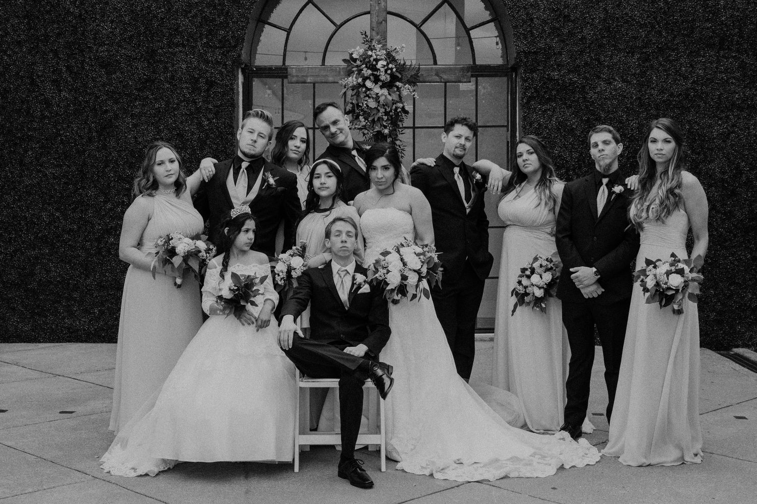 Wedding party poses together in formal black and white group photos in front of an elegant arched doorway.