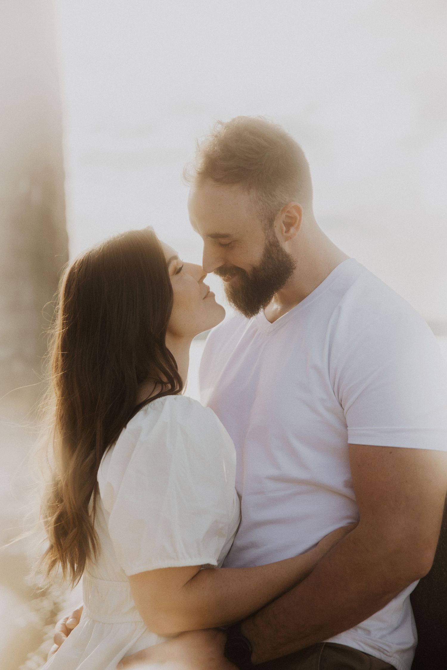 A tender embrace captured in bright sunlight against a white background.