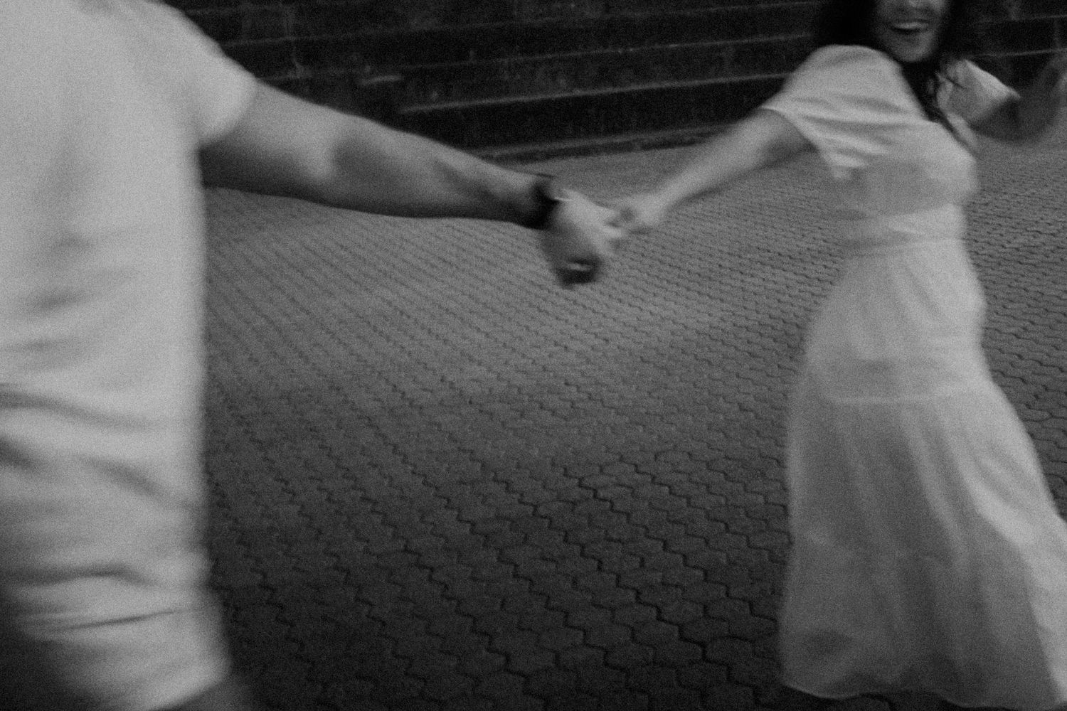Motion blur captures a couple dancing on patterned brick ground.