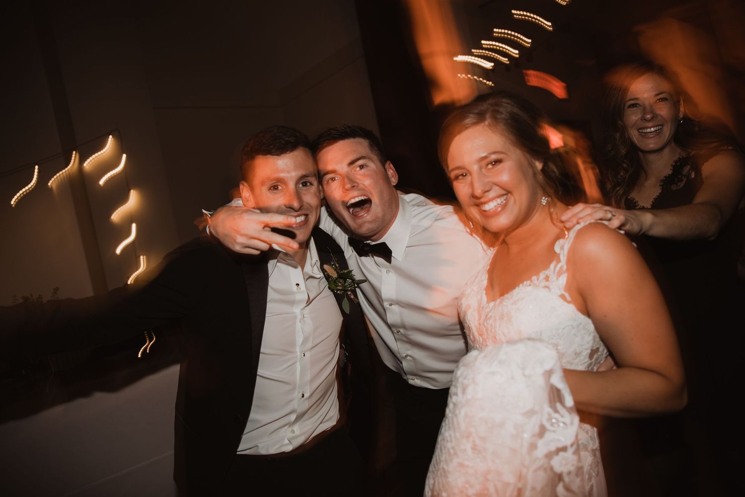 Wedding party guests dancing and celebrating in a dark reception venue.