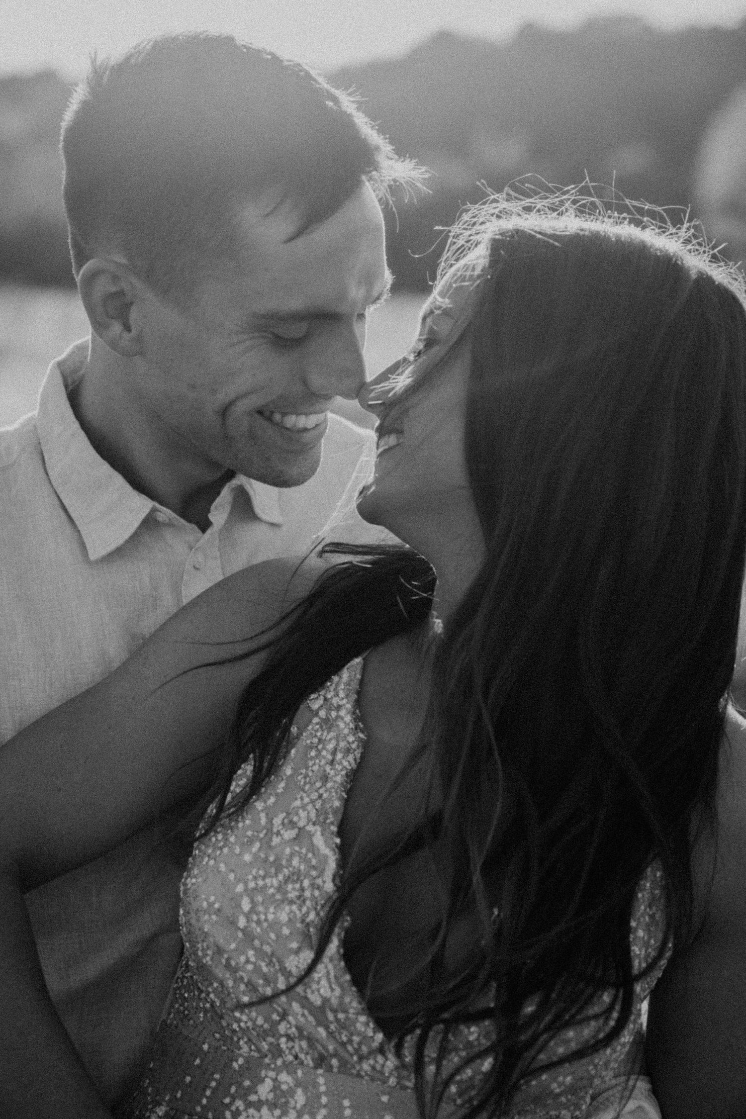 Sun-kissed couple sharing joyful moment in black and white photography.