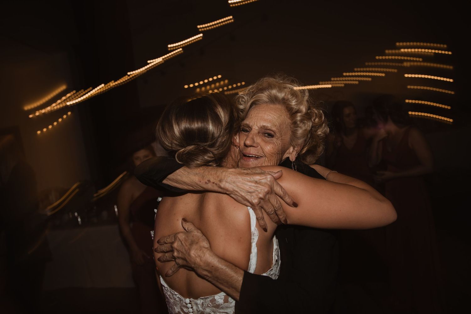 Guests dancing and embracing during lively wedding reception celebration.