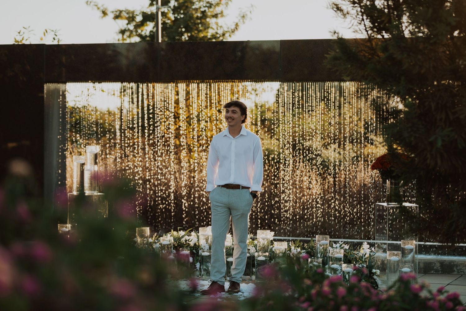 Person standing in front of a romantic curtain of string lights at dusk in a garden setting.