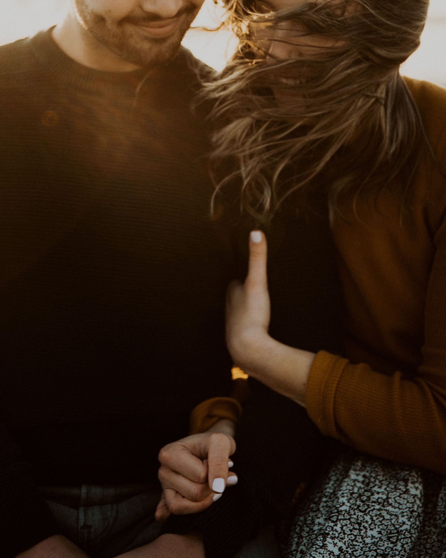 Intimate couple in warm sunlight sharing a tender moment while holding hands.