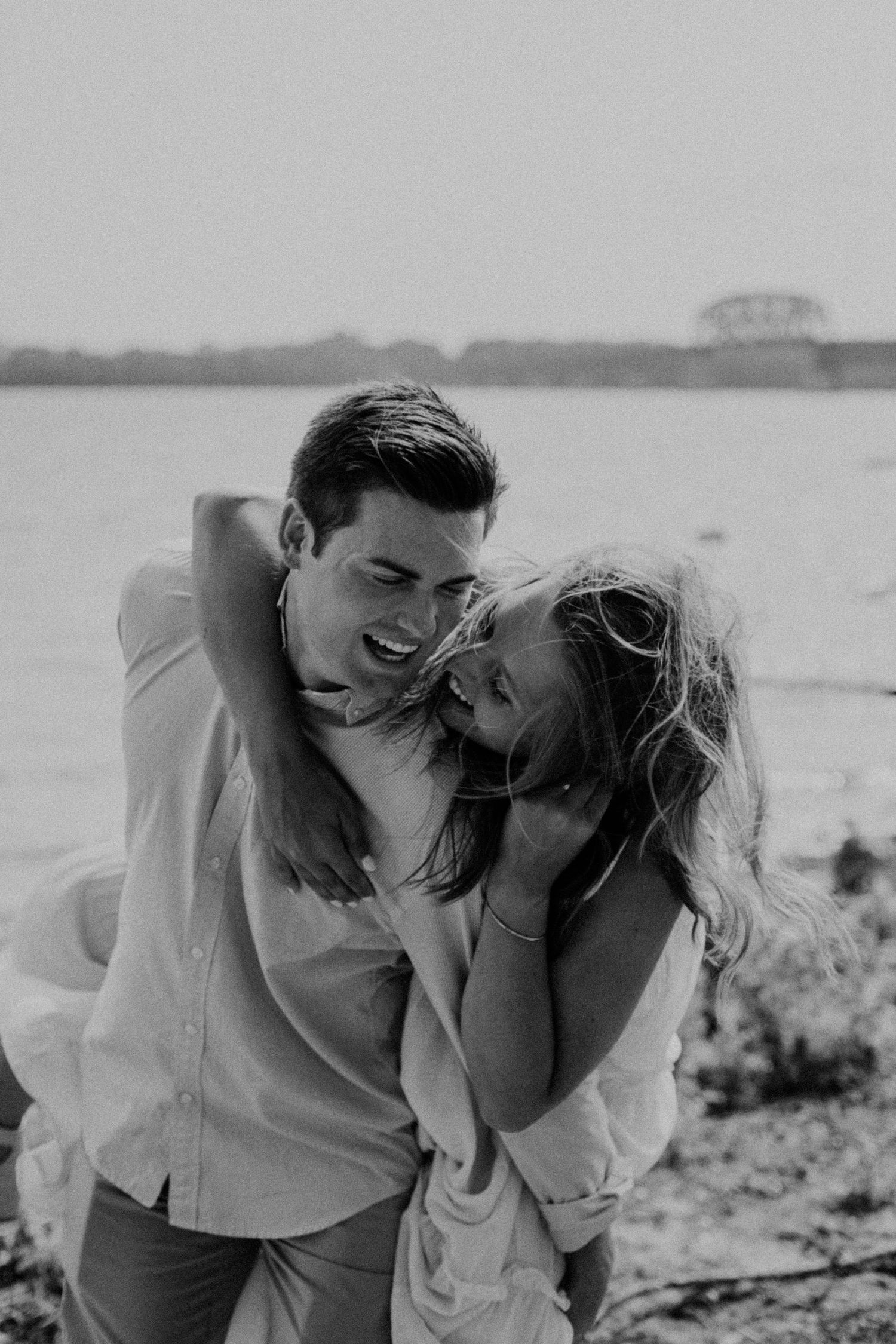 A romantic black and white photo sequence of a couple laughing together on a beach.