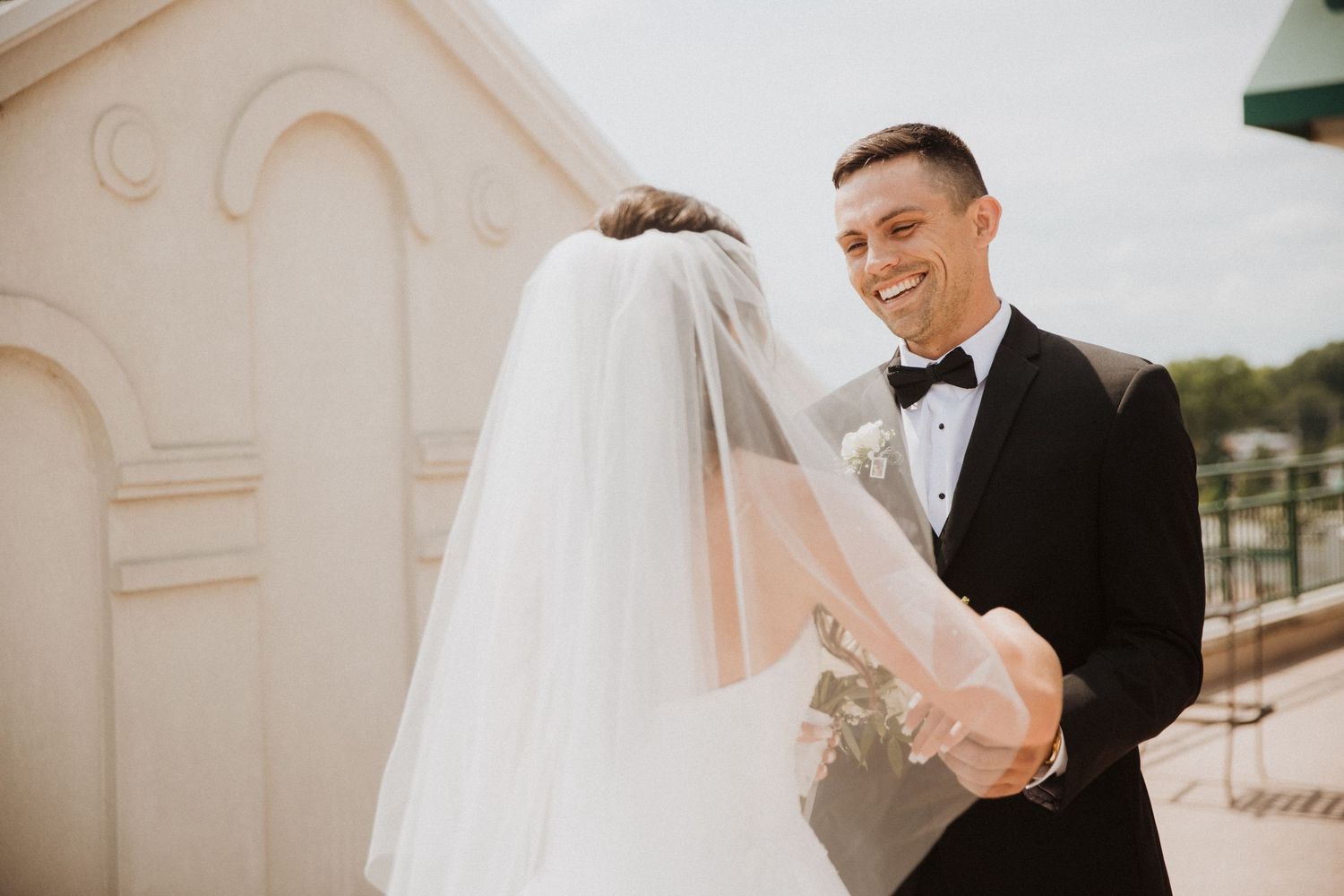 First look moment captured at an elegant white building with classical architecture.