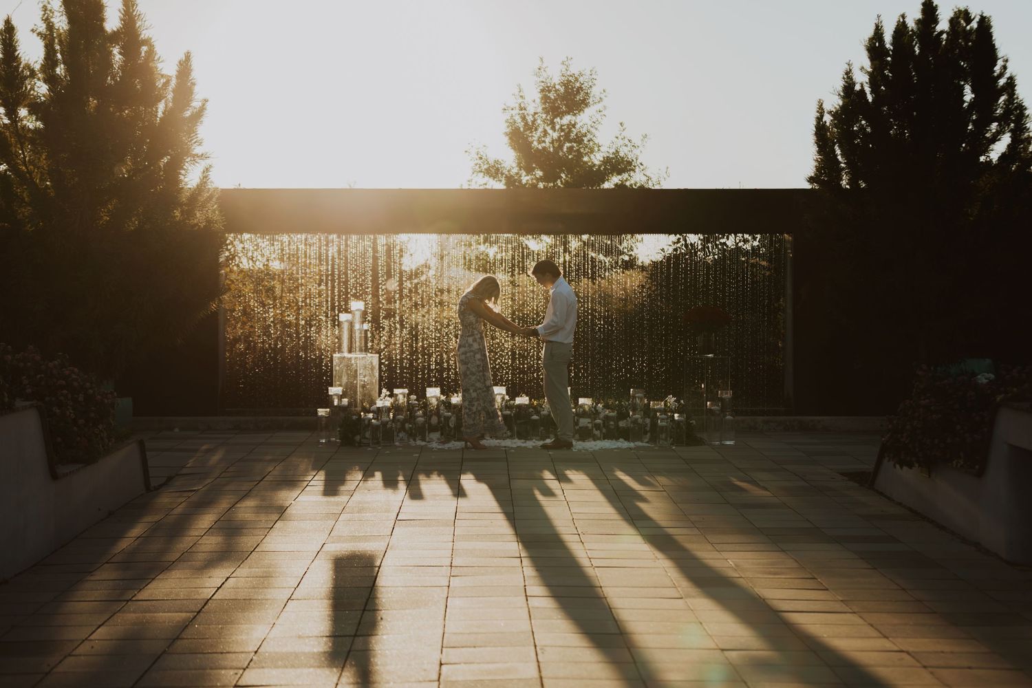 Sunset casts dramatic shadows through hanging string lights on an outdoor patio.