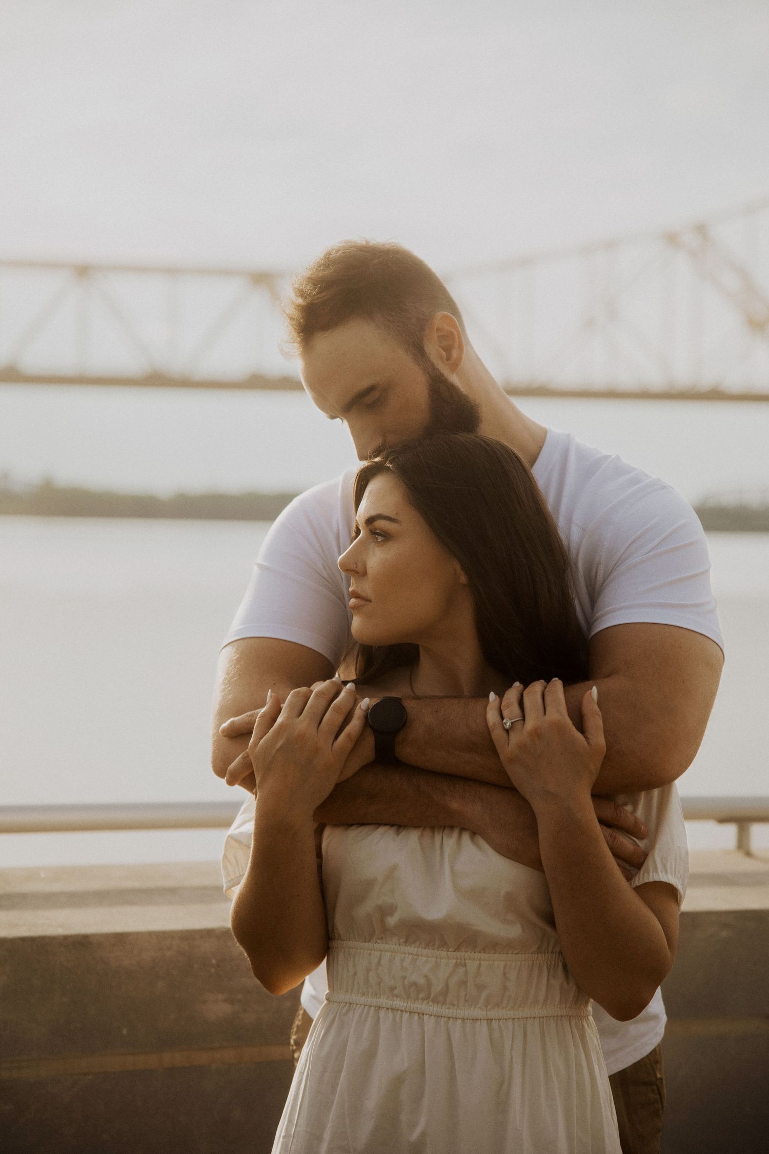 Romantic couple embracing in white clothing against a bright background.