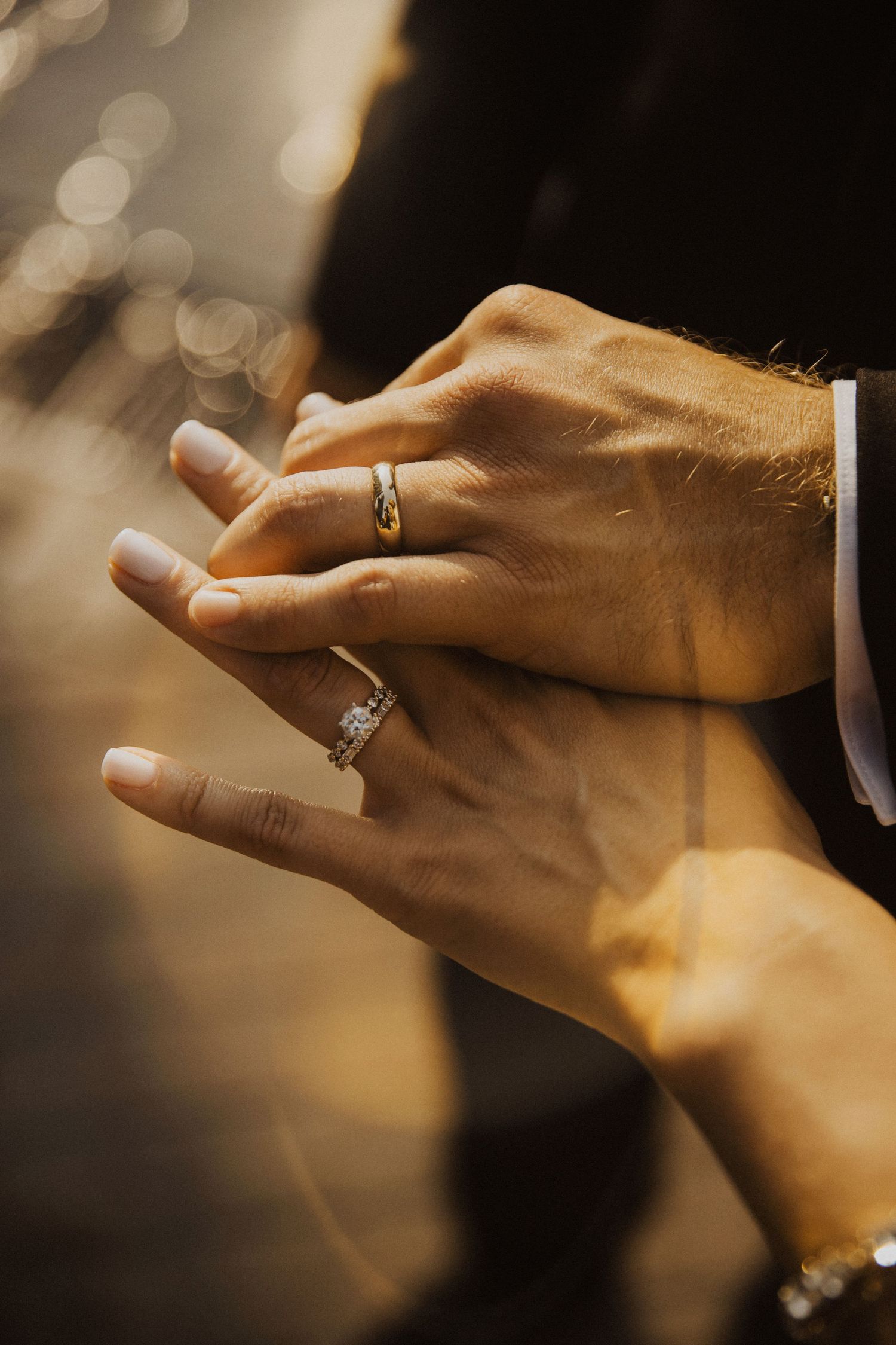 Close-up of hands exchanging wedding rings during ceremony in warm golden light.