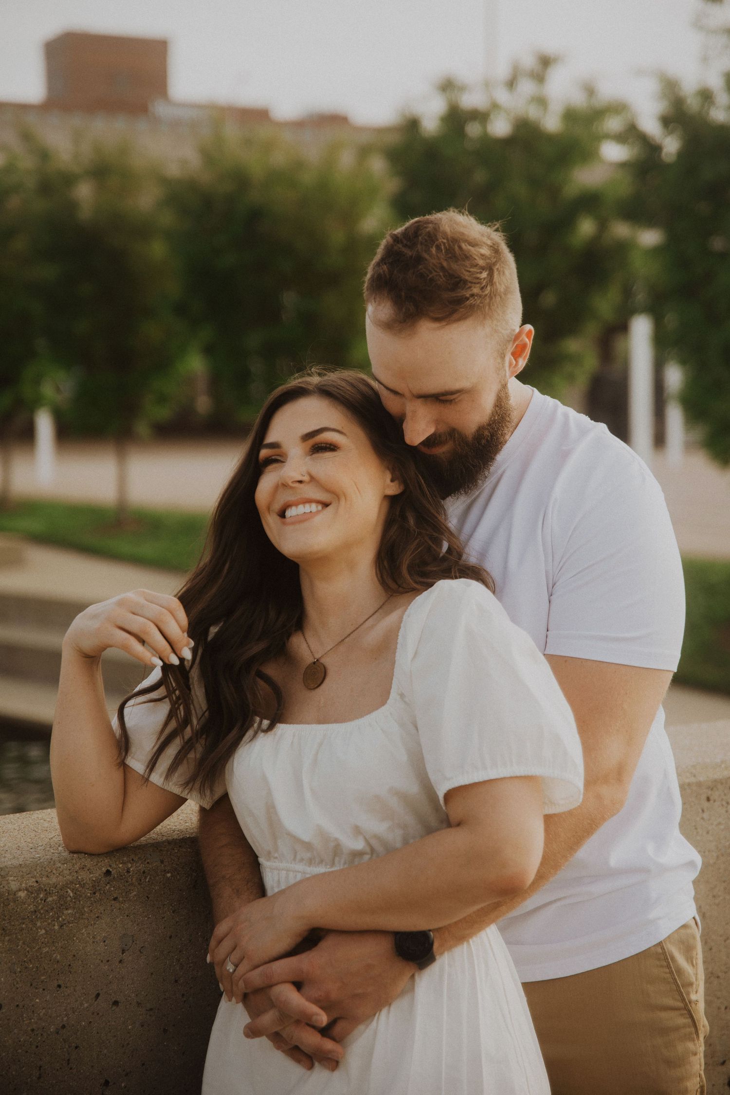 A couple shares playful moments against an urban backdrop at sunset.