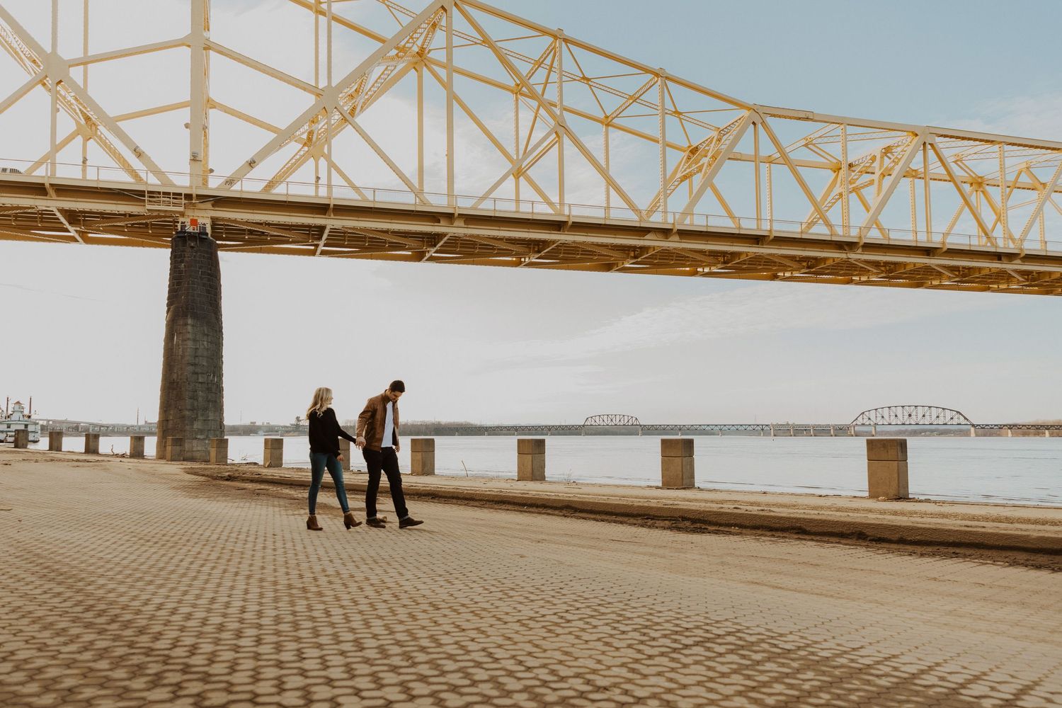 A wide landscape shot of a bridge with distant figures walking.