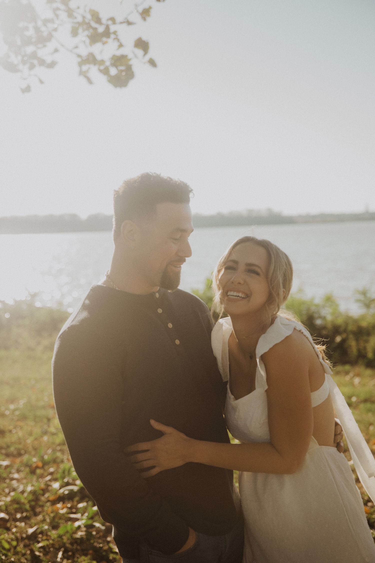 Couple embracing and laughing together in golden sunlight on autumn day.