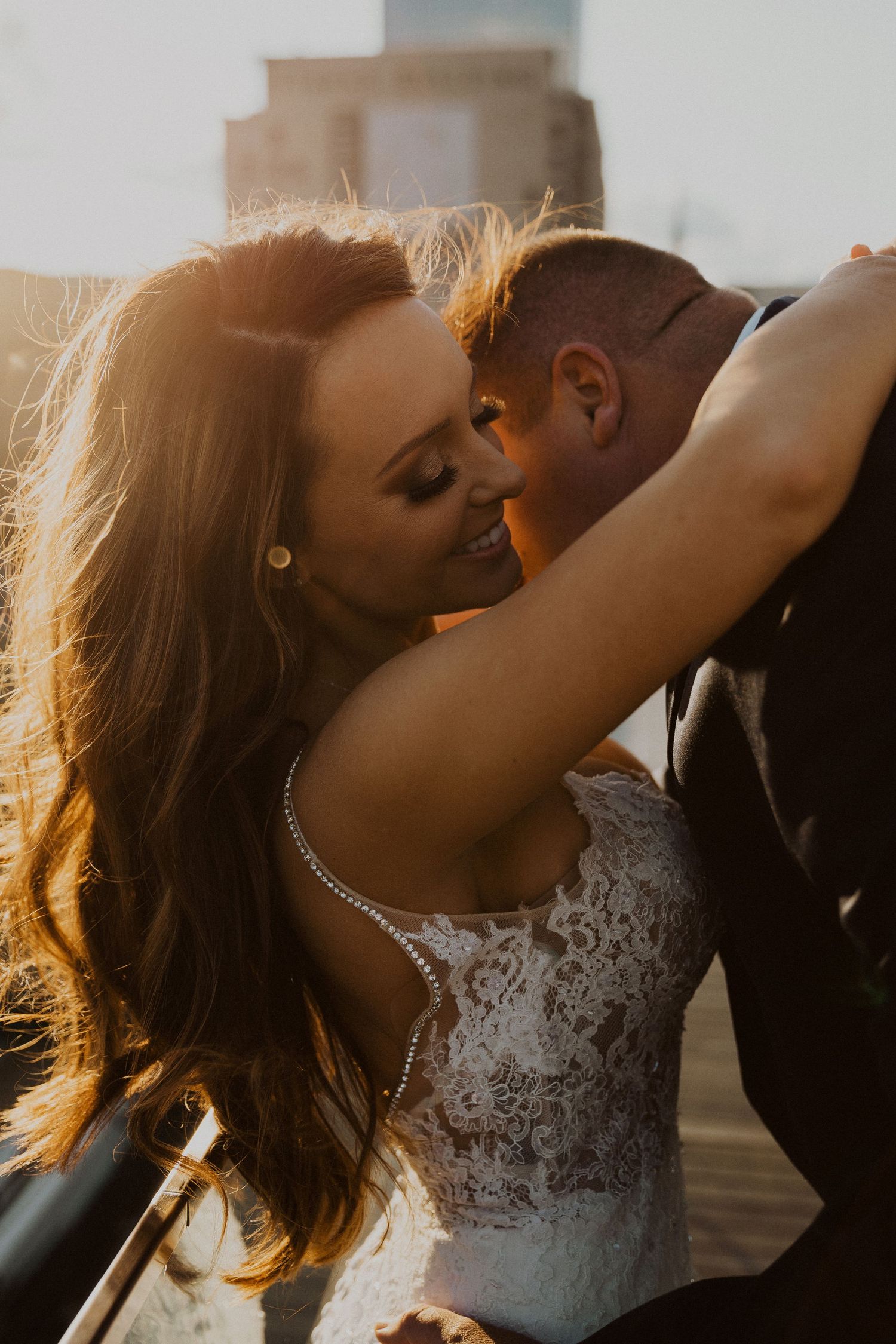 A romantic sunset moment between newlyweds with the bride wearing a detailed lace wedding dress.