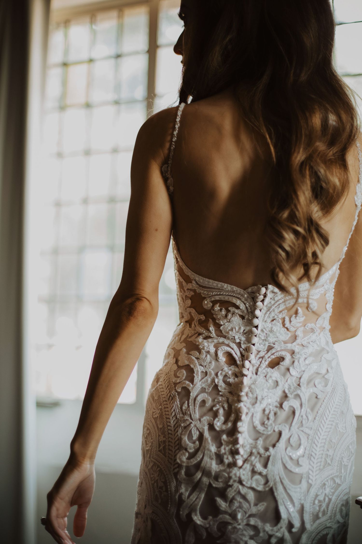 Close-up details of an intricate lace wedding dress back with delicate floral patterns.