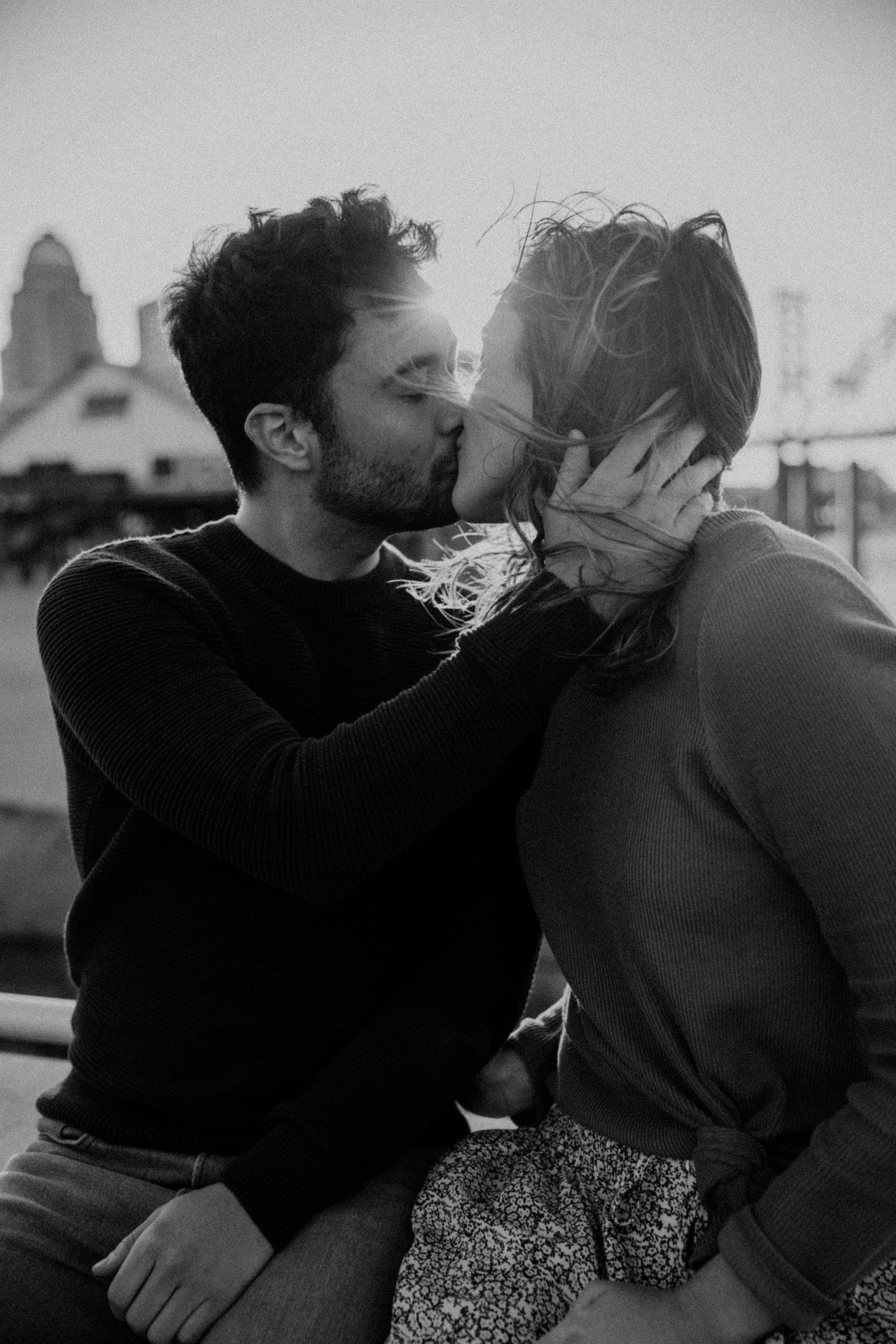 Romantic black and white photo of couple kissing outdoors.