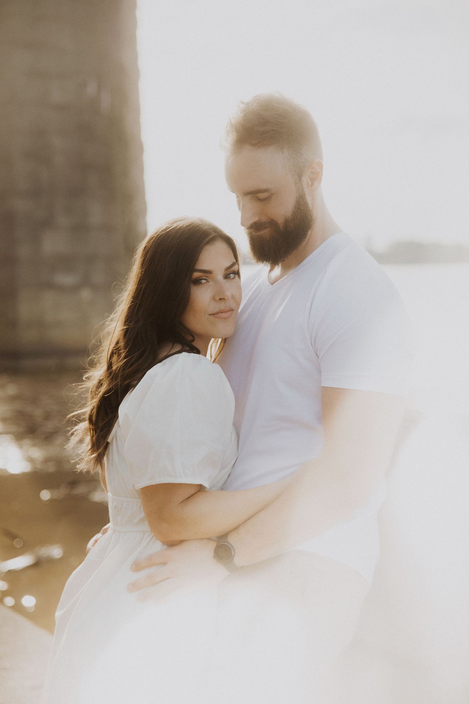 A couple shares an intimate moment in soft sunlit photography.